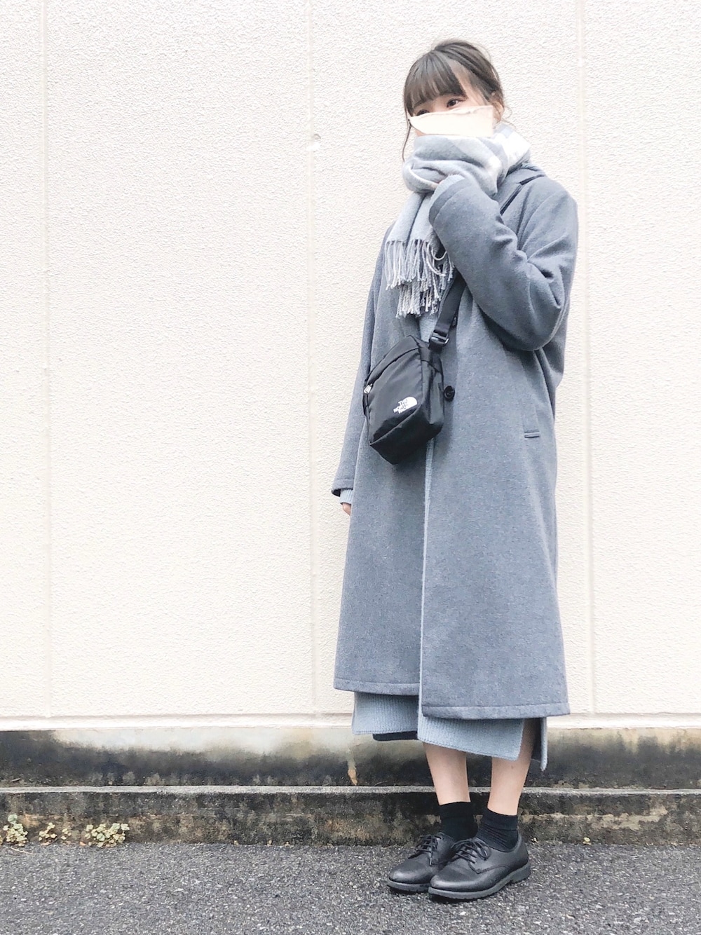 グレー系のチェスターコート、グリーン系のワンピース、ブラック系のショルダーバッグを着用したレディースの春コーディネートの1枚目の写真