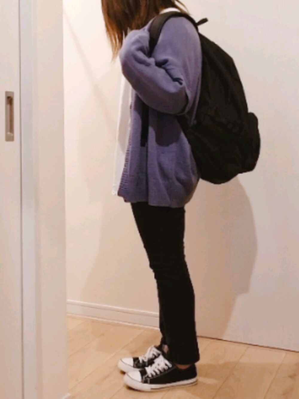 ブルー系のニット/セーター、ホワイト系のTシャツ/カットソー、ブラック系のバックパック/リュックを着用したレディースの春コーディネートの1枚目の写真