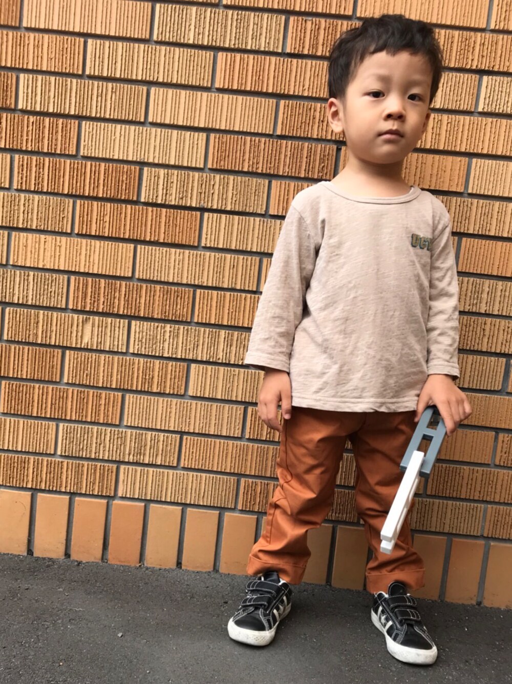 オレンジ系のチノパンツ、ブラック系のスニーカーを着用したキッズの春コーディネートの1枚目の写真