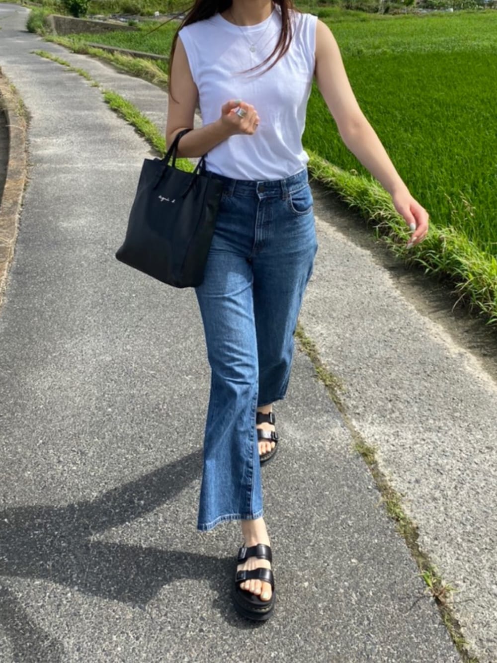 ブラック系のサンダル、ホワイト系のタンクトップ、ブルー系のデニムパンツを着用したレディースの夏コーディネートの1枚目の写真