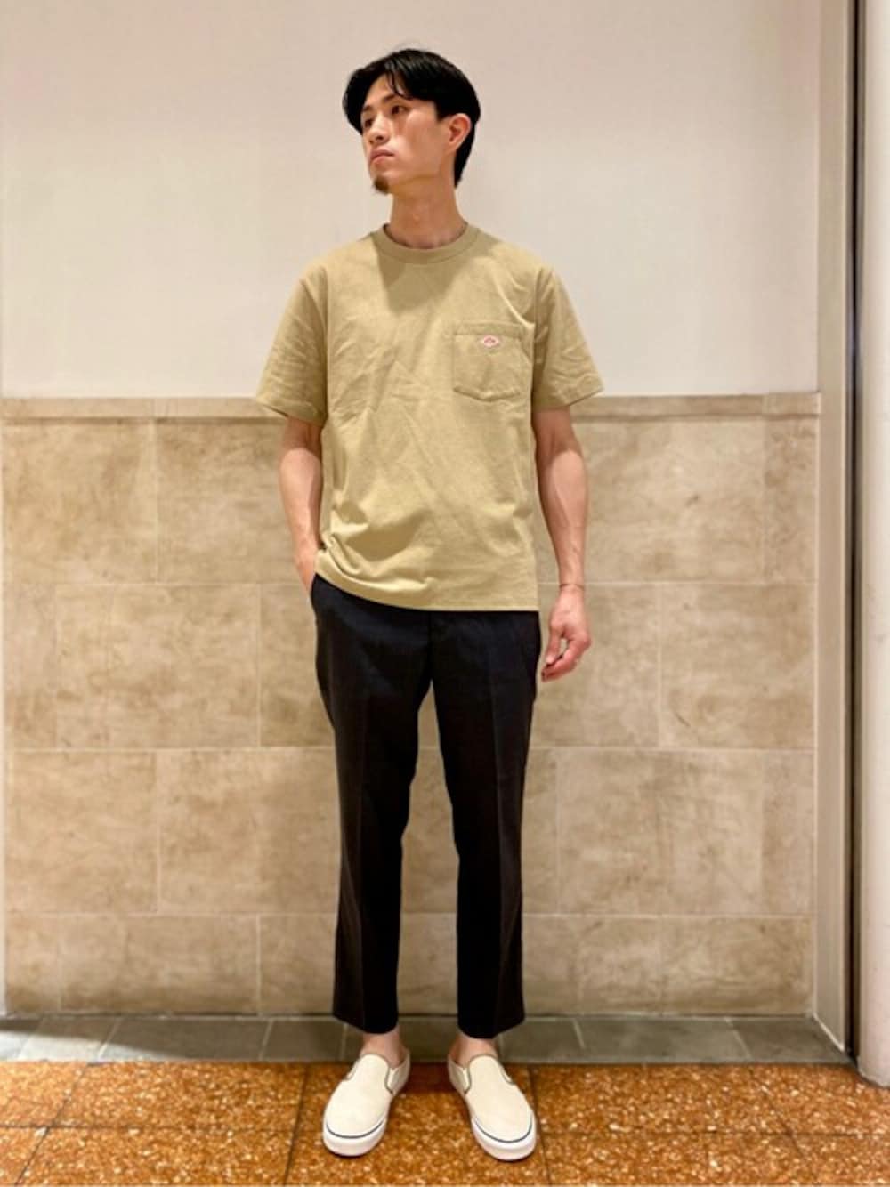 ベージュ系のTシャツ/カットソー、グレー系のスラックス、ホワイト系のスニーカーを着用したメンズの夏コーディネートの1枚目の写真