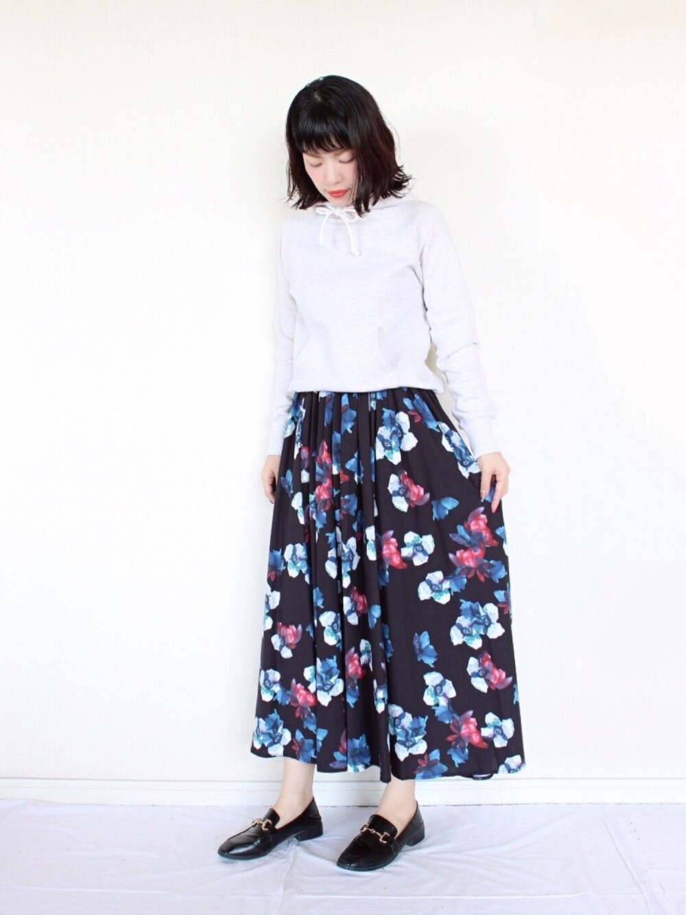 ホワイト系のパーカー、ブラック系のスカート、ブラック系のローファーを着用したレディースの冬コーディネートの1枚目の写真