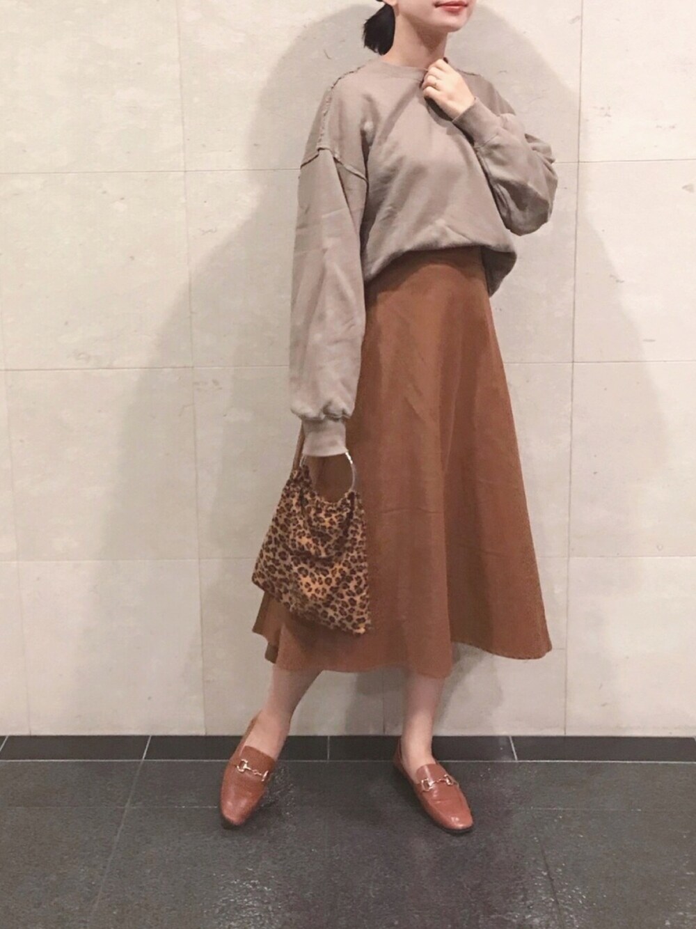 ブラウン系のスカート、ブラウン系のスウェット、イエロー系のハンドバッグを着用したレディースの秋コーディネートの1枚目の写真