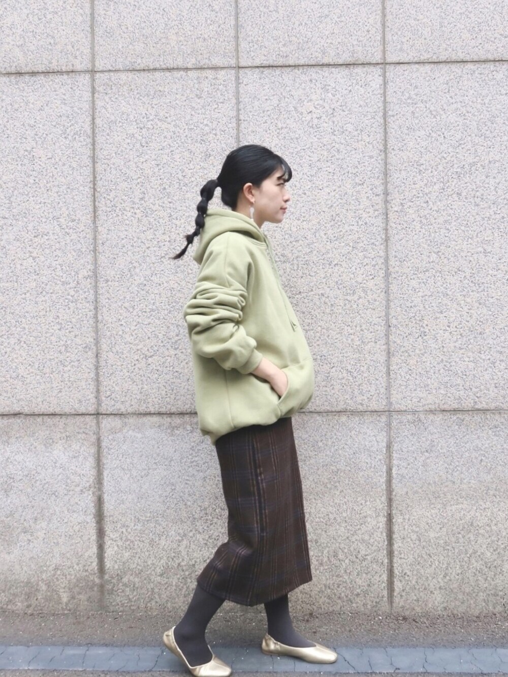 グリーン系のパーカー、ブラウン系のスカート、ゴールド系のパンプスを着用したレディースの冬コーディネートの1枚目の写真