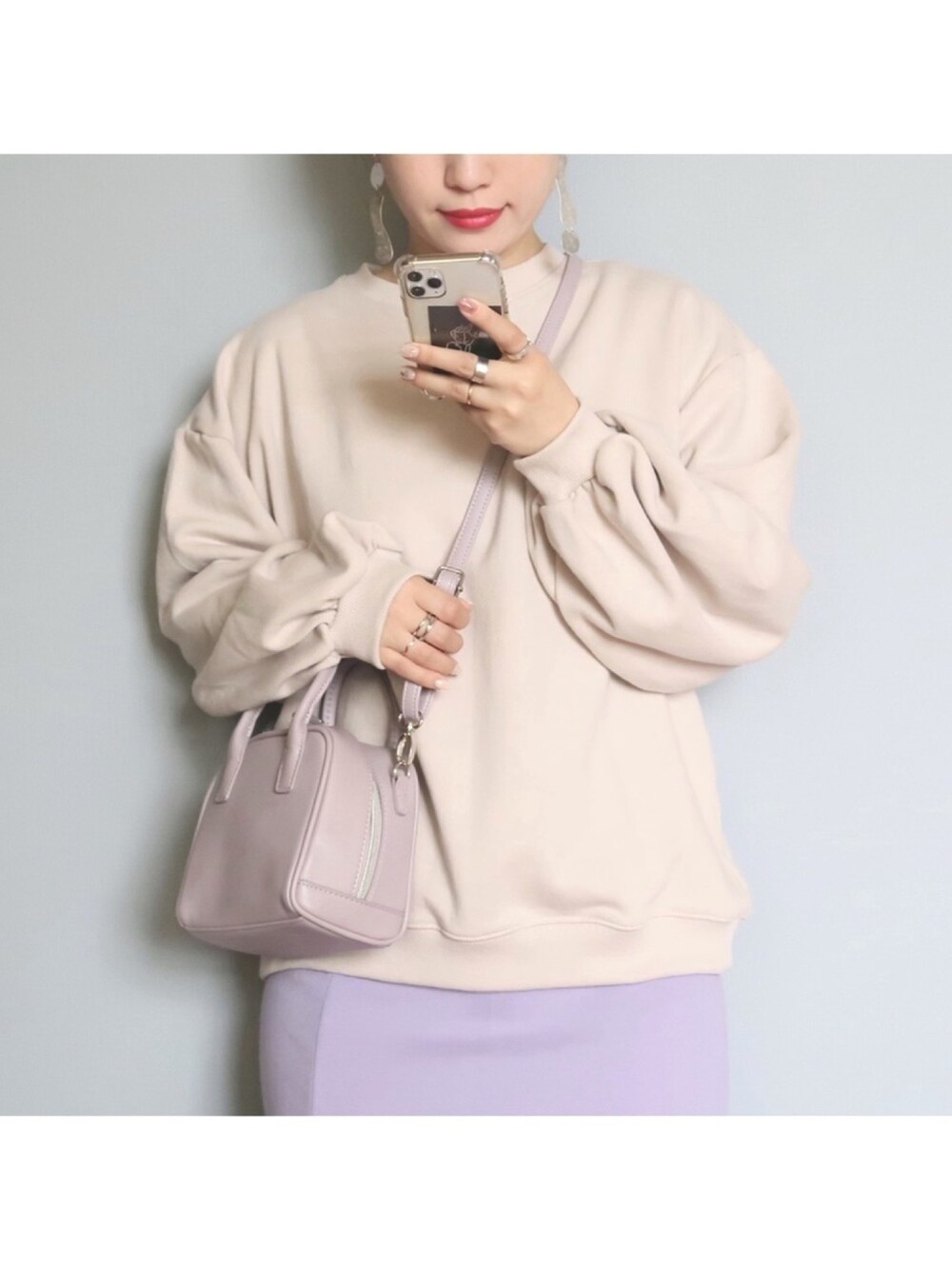 ベージュ系のスウェット、パープル系のバッグ、パープル系のスカートを着用したレディースの冬コーディネートの1枚目の写真