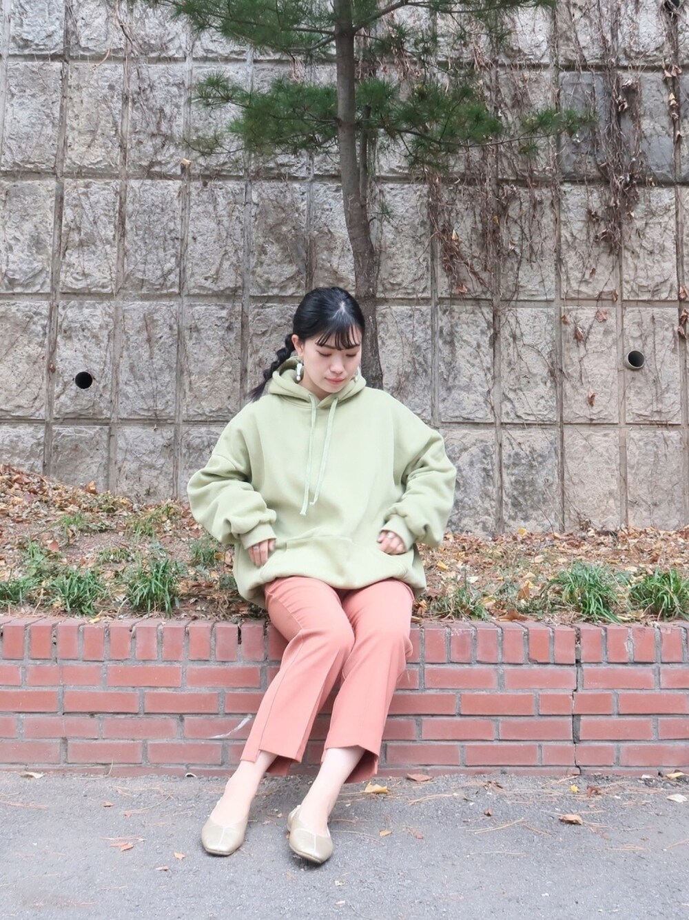 グリーン系のパーカー、ピンク系のパンツ、ゴールド系のパンプスを着用したレディースの冬コーディネートの1枚目の写真