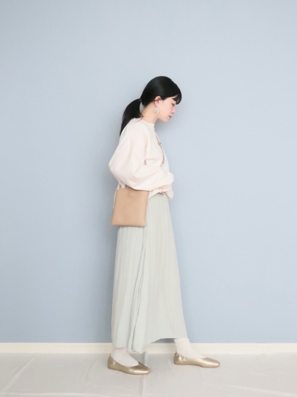 ホワイト系のスウェット、ベージュ系のバッグ、グリーン系のスカートを着用したレディースの冬コーディネートの1枚目の写真