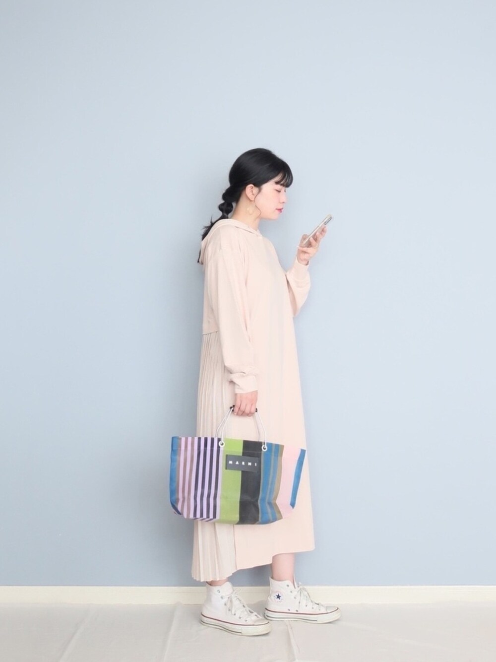 ベージュ系のワンピース、グリーン系のバッグ、ホワイト系のスニーカーを着用したレディースの春コーディネートの1枚目の写真