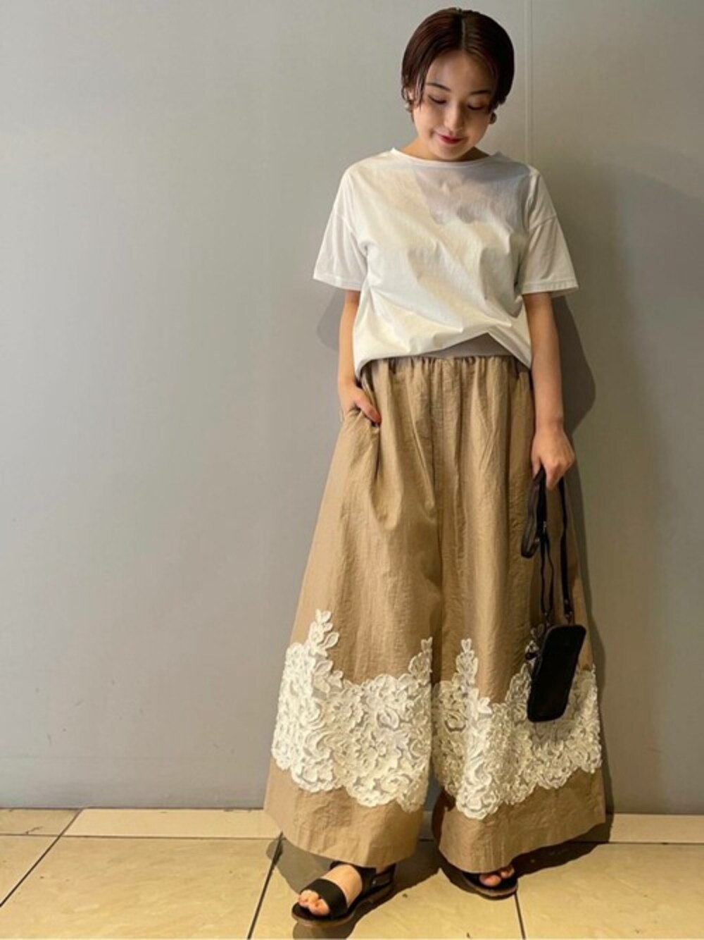ホワイト系のTシャツ/カットソー、ブラウン系のその他パンツ、ブラック系のトートバッグを着用したレディースの春コーディネートの1枚目の写真