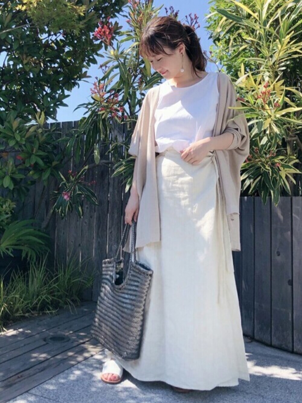 ベージュ系のカーディガン/ボレロ、ホワイト系のタンクトップ、ホワイト系のスカートを着用したレディースの春コーディネートの1枚目の写真