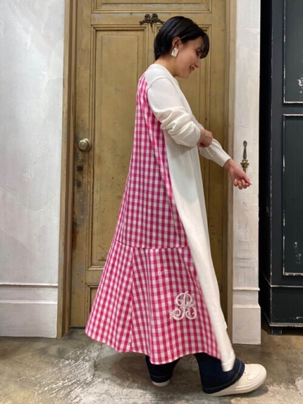 ホワイト系のワンピース、ブルー系のデニムパンツ、シルバー系のスニーカーを着用したレディースの春コーディネートの1枚目の写真