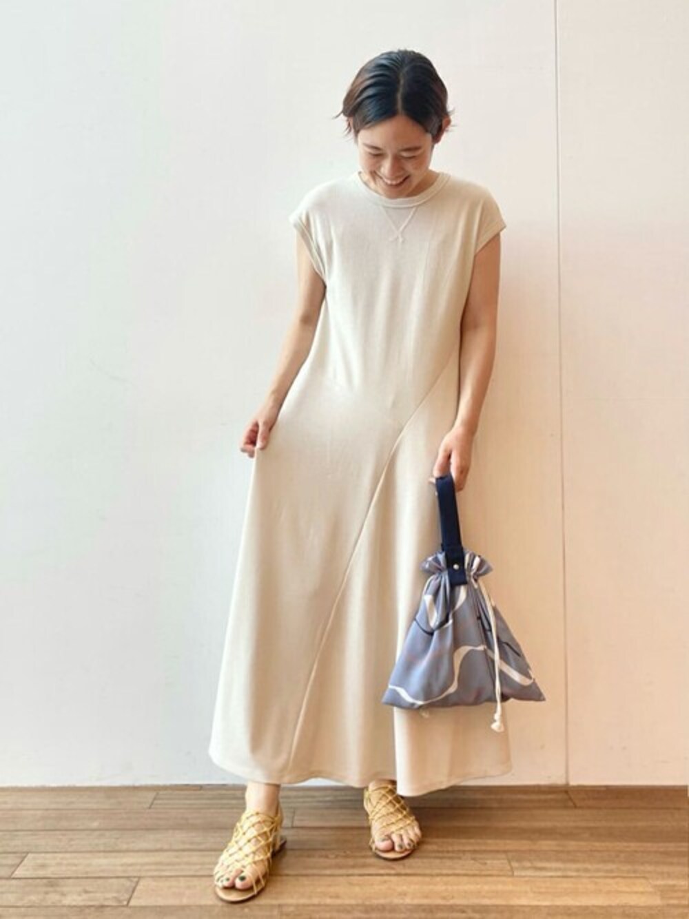 ベージュ系のワンピース、ブルー系のトートバッグを着用したレディースの夏コーディネートの1枚目の写真