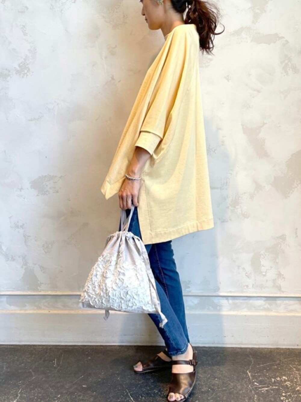 イエロー系のTシャツ/カットソー、ブルー系のデニムパンツ、グレー系のトートバッグを着用したレディースの夏コーディネートの1枚目の写真