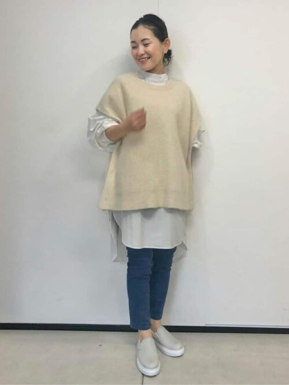 ホワイト系のニット/セーター、ホワイト系のシャツ/ブラウス、ブルー系のデニムパンツを着用したレディースの秋コーディネートの1枚目の写真