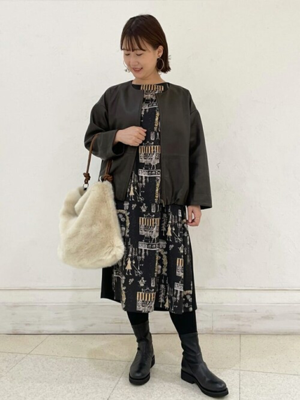 ブラウン系のブルゾン、ブラック系のワンピース、ホワイト系のショルダーバッグを着用したレディースの秋コーディネートの1枚目の写真