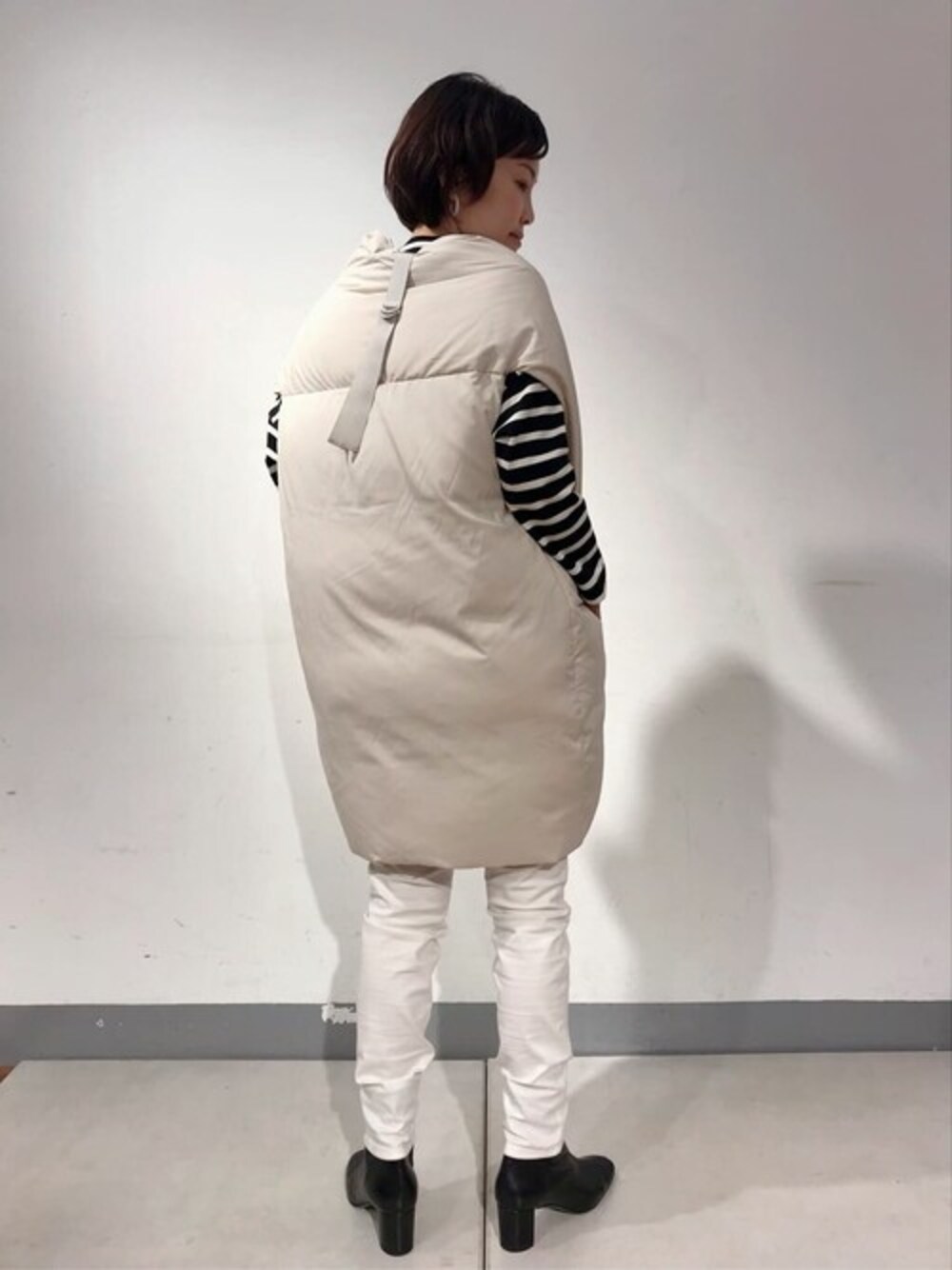 ホワイト系のダウンベスト、ブラック系のTシャツ/カットソー、ホワイト系のその他パンツを着用したレディースの秋コーディネートの1枚目の写真