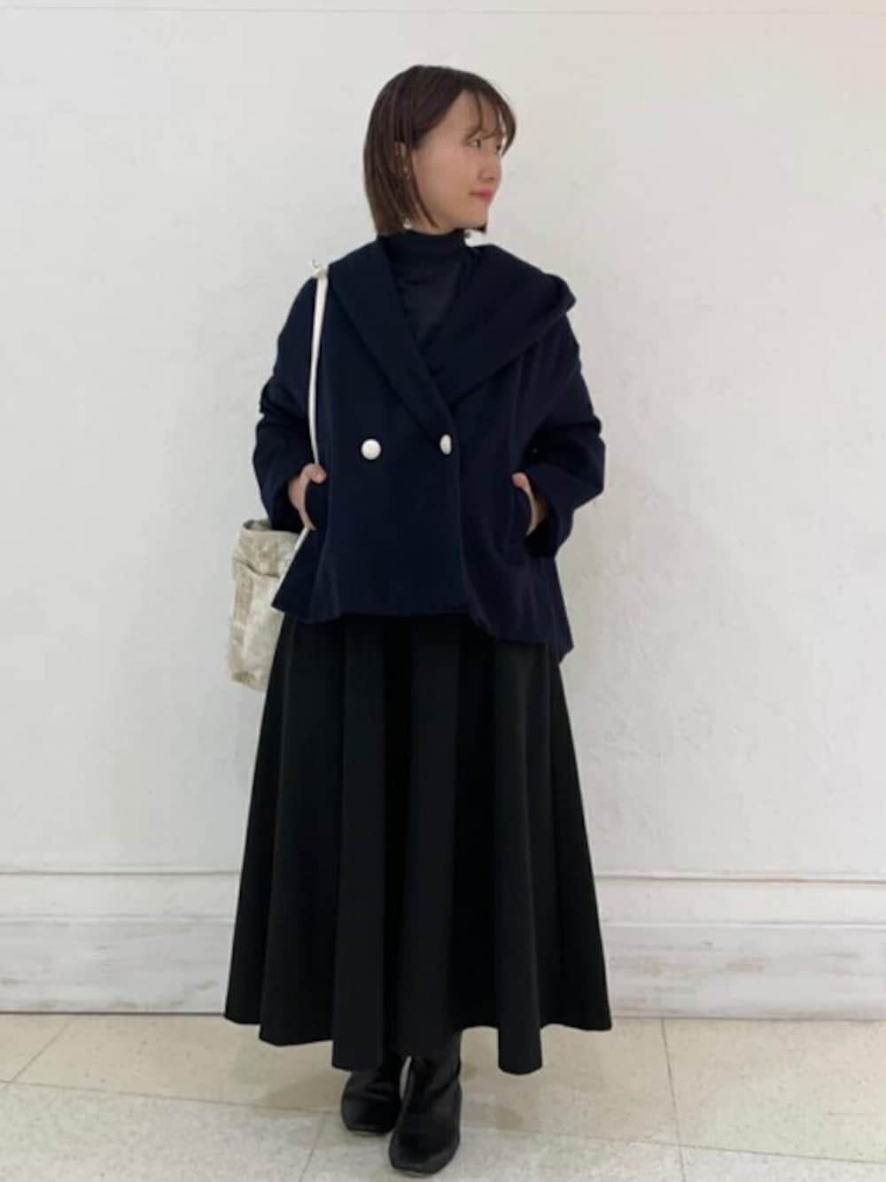 ブルー系のテーラードジャケット、ブラック系のワンピース、ベージュ系のトートバッグを着用したレディースの秋コーディネートの1枚目の写真