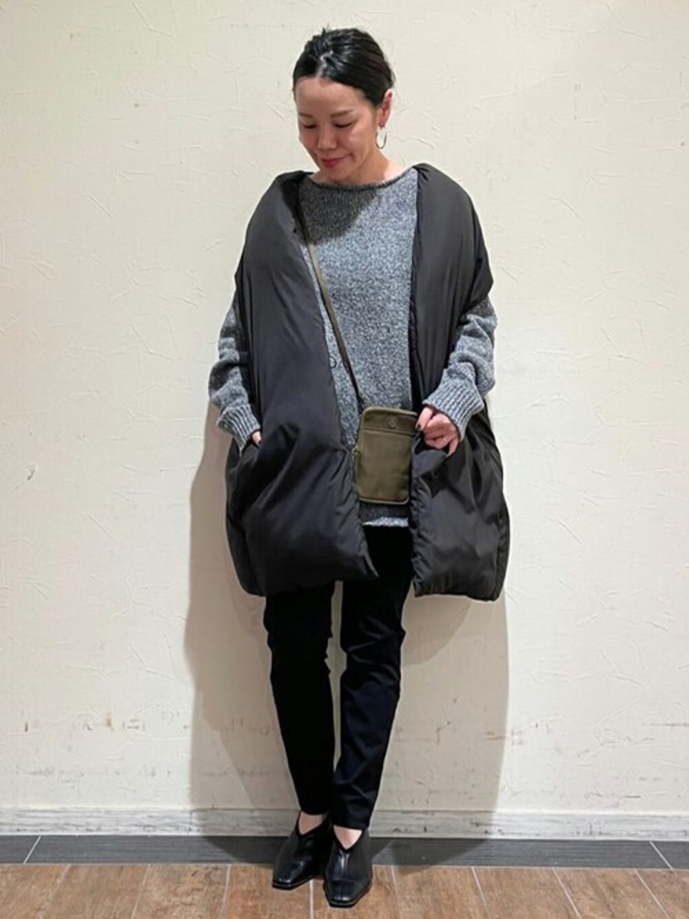 ブラック系のダウンベスト、グレー系のニット/セーター、ブラック系のその他パンツを着用したレディースの秋コーディネートの1枚目の写真