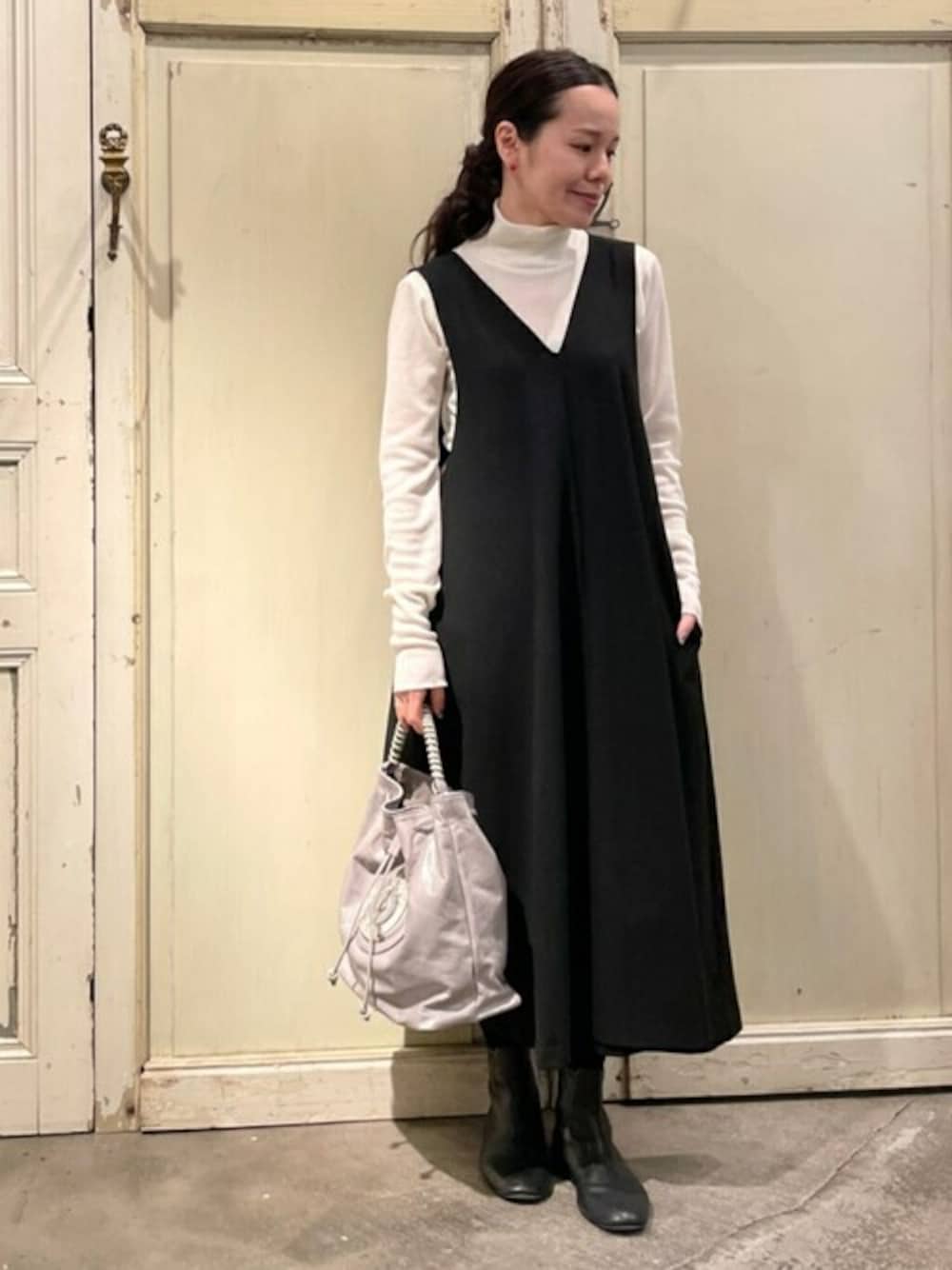 ブラック系のワンピース、ホワイト系のニット/セーター、グレー系のショルダーバッグを着用したレディースの冬コーディネートの1枚目の写真