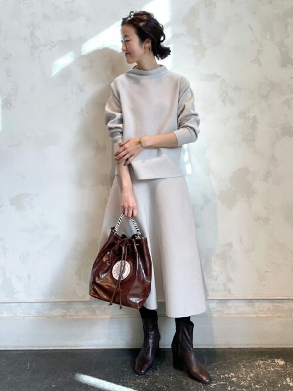 ベージュ系のスカート、ブラウン系のショルダーバッグ、ベージュ系のTシャツ/カットソーを着用したレディースの冬コーディネートの1枚目の写真