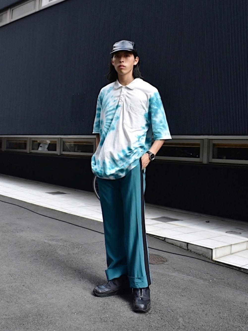 ホワイト系のポロシャツ、ブルー系のパンツ、ブラック系のスニーカーを着用したメンズの夏コーディネートの1枚目の写真