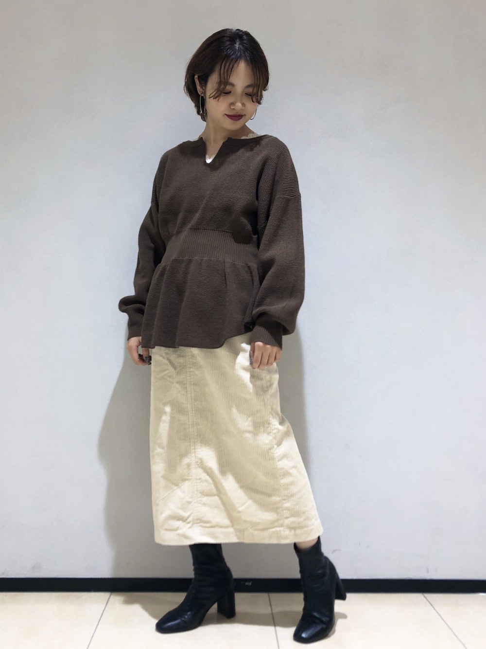 ブラウン系のニット/セーター、ホワイト系のスカート、ブラック系のブーツを着用したレディースの冬コーディネートの1枚目の写真