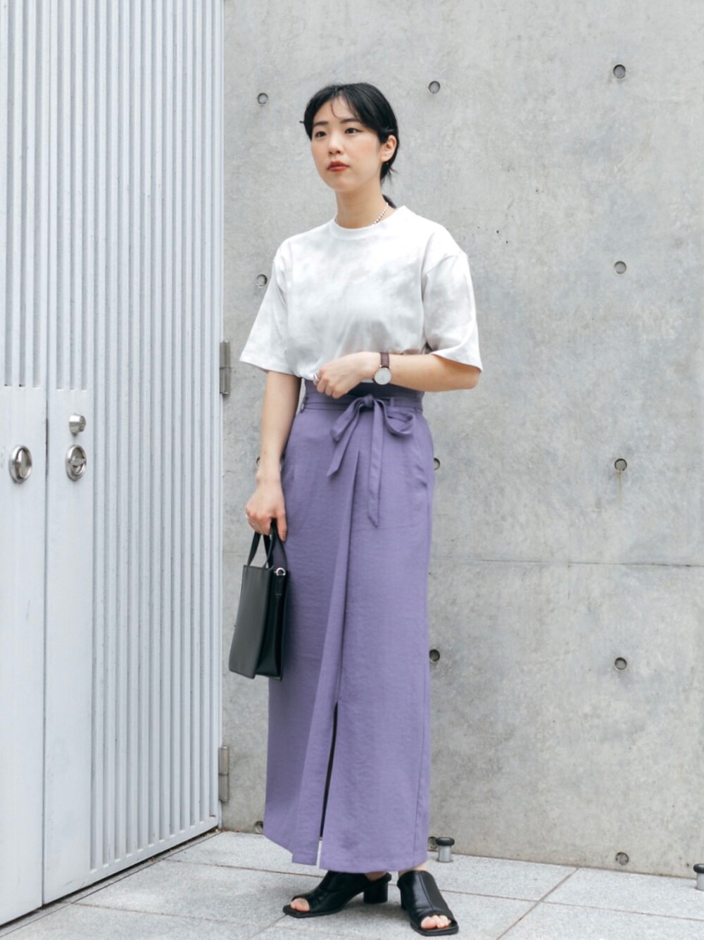 パープル系のスカート、ベージュ系のTシャツ/カットソー、ブラック系のショルダーバッグを着用したレディースの春コーディネートの1枚目の写真