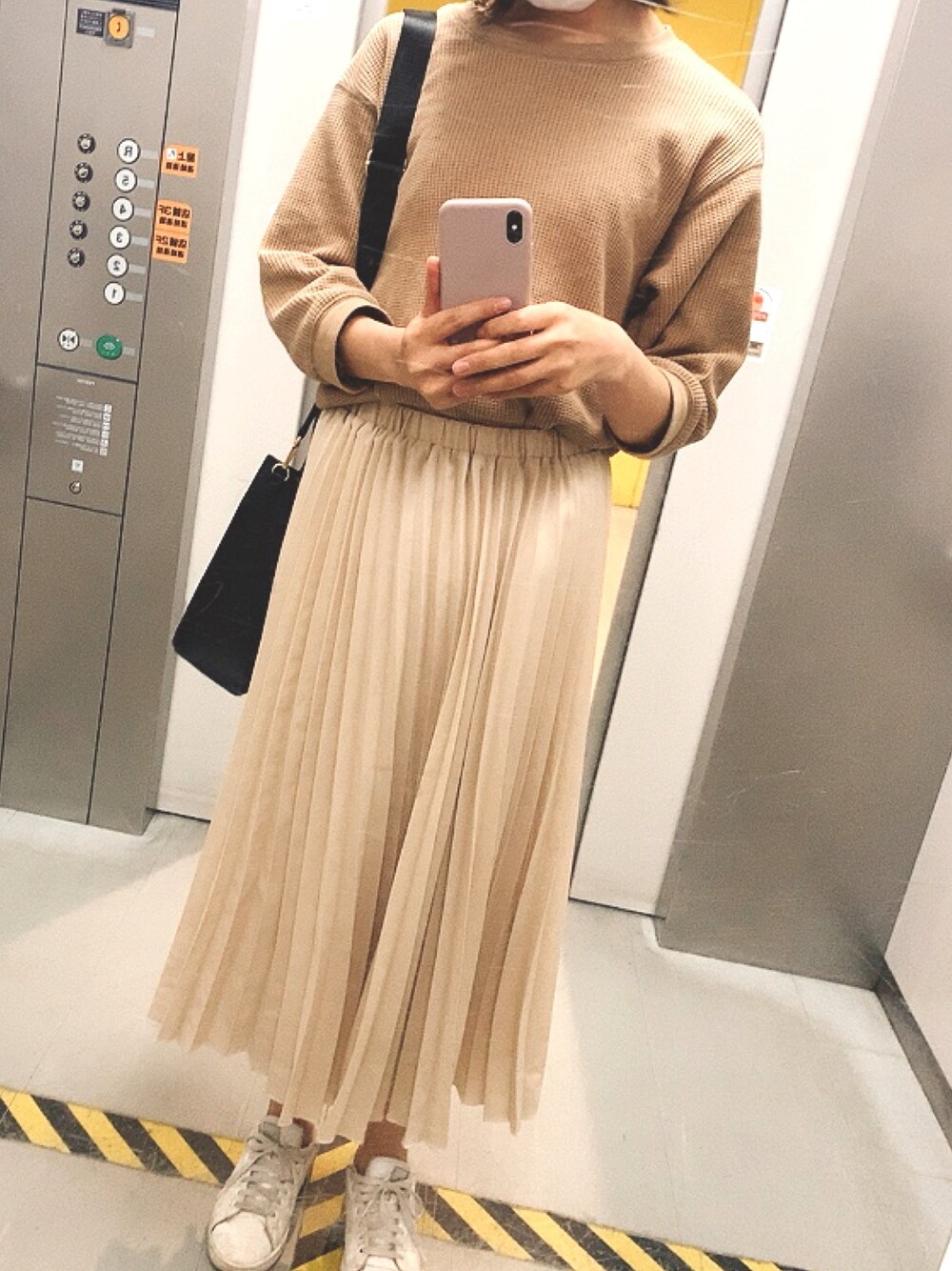 ベージュ系のスカート、ブラウン系のTシャツ/カットソー、ホワイト系のスニーカーを着用したレディースの春コーディネートの1枚目の写真