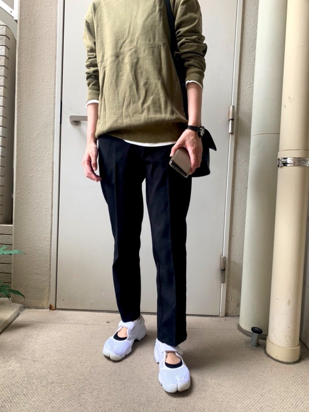 グリーン系のニット/セーター、ホワイト系のTシャツ/カットソー、ブラック系のショルダーバッグを着用したレディースの秋コーディネートの1枚目の写真