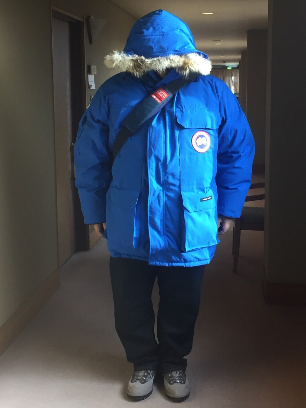 ブルー系のダウンジャケット/コート、ブルー系のメッセンジャーバッグ、ブルー系のデニムパンツを着用したメンズの冬コーディネートの1枚目の写真