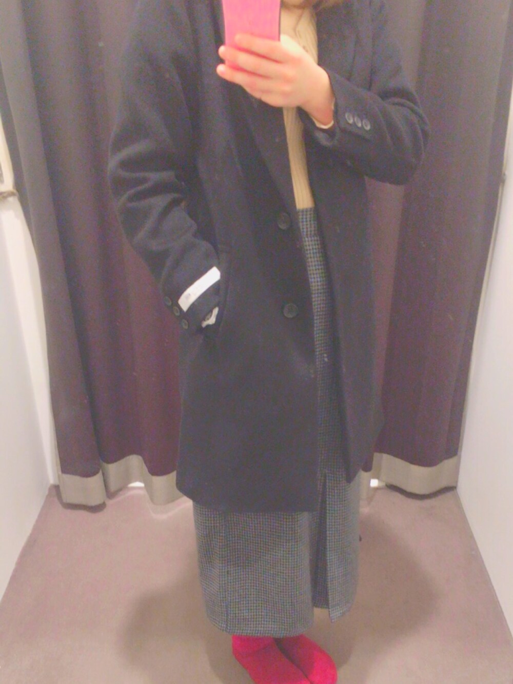 ブラック系のチェスターコート、ホワイト系のニット/セーター、グレー系のスカートを着用したレディースの冬コーディネートの1枚目の写真