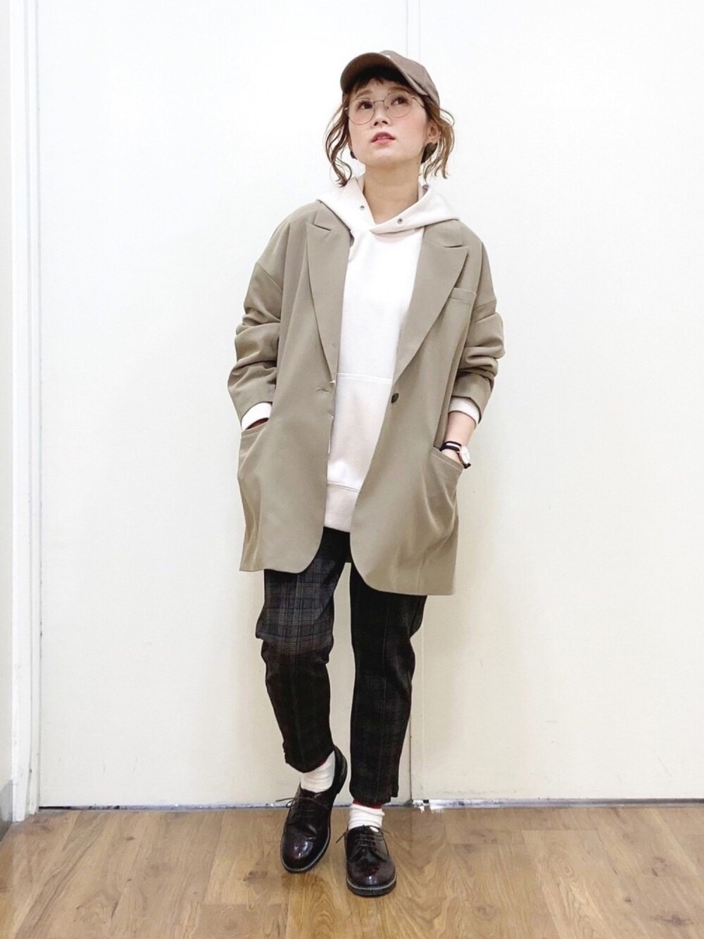 ホワイト系のパーカー、ブラウン系のテーラードジャケット、ブラック系のスラックスを着用したレディースの冬コーディネートの1枚目の写真