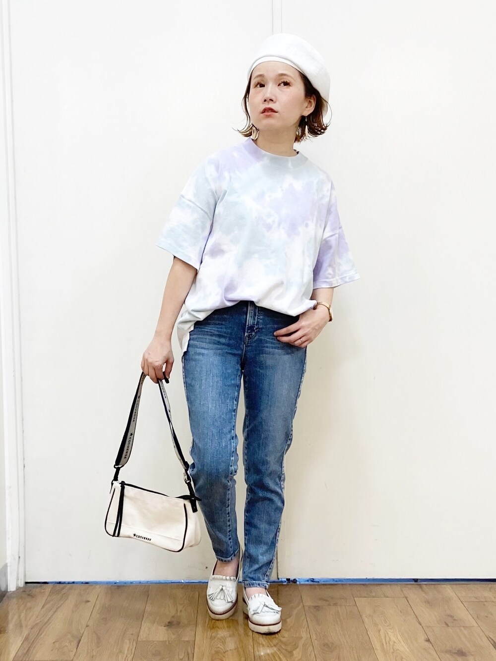 パープル系のTシャツ/カットソー、ホワイト系のショルダーバッグ、ブルー系のデニムパンツを着用したレディースの春コーディネートの1枚目の写真