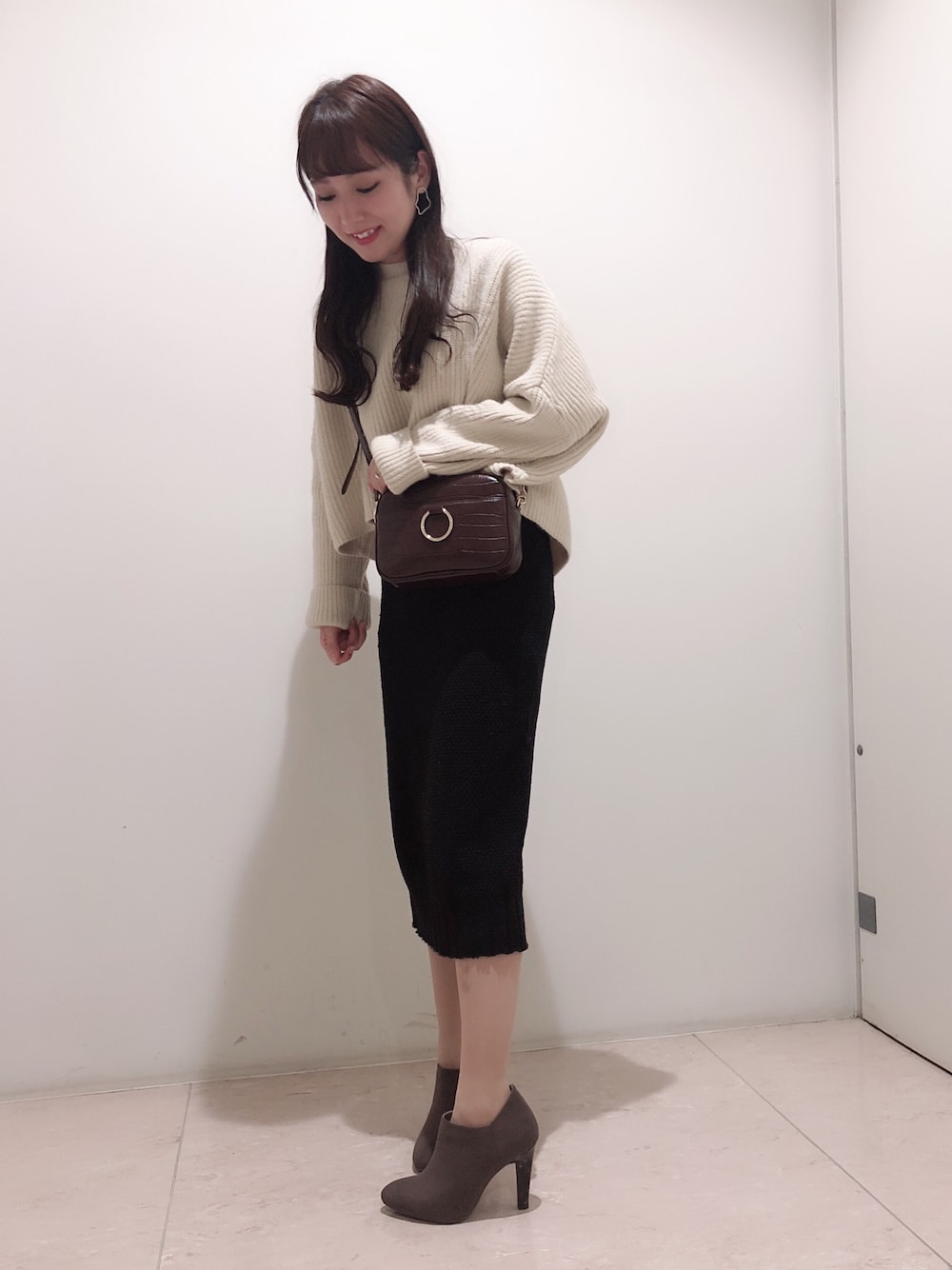 ブラウン系のショルダーバッグ、グレー系のブーツを着用したレディースの秋コーディネートの1枚目の写真