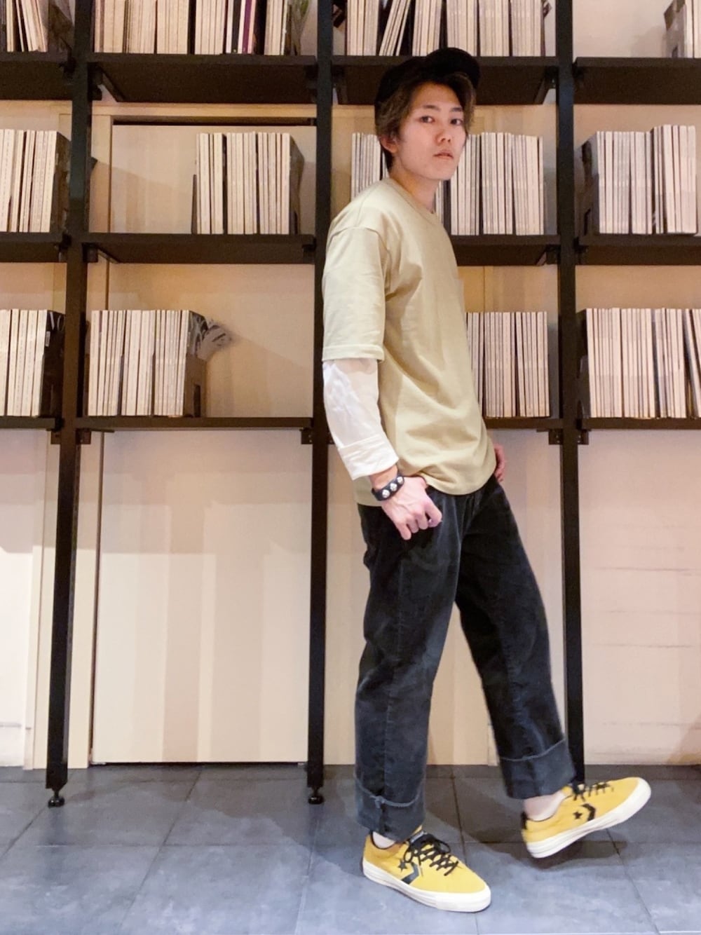 ブラック系のパンツ、グリーン系のTシャツ/カットソー、イエロー系のスニーカーを着用したメンズの春コーディネートの1枚目の写真