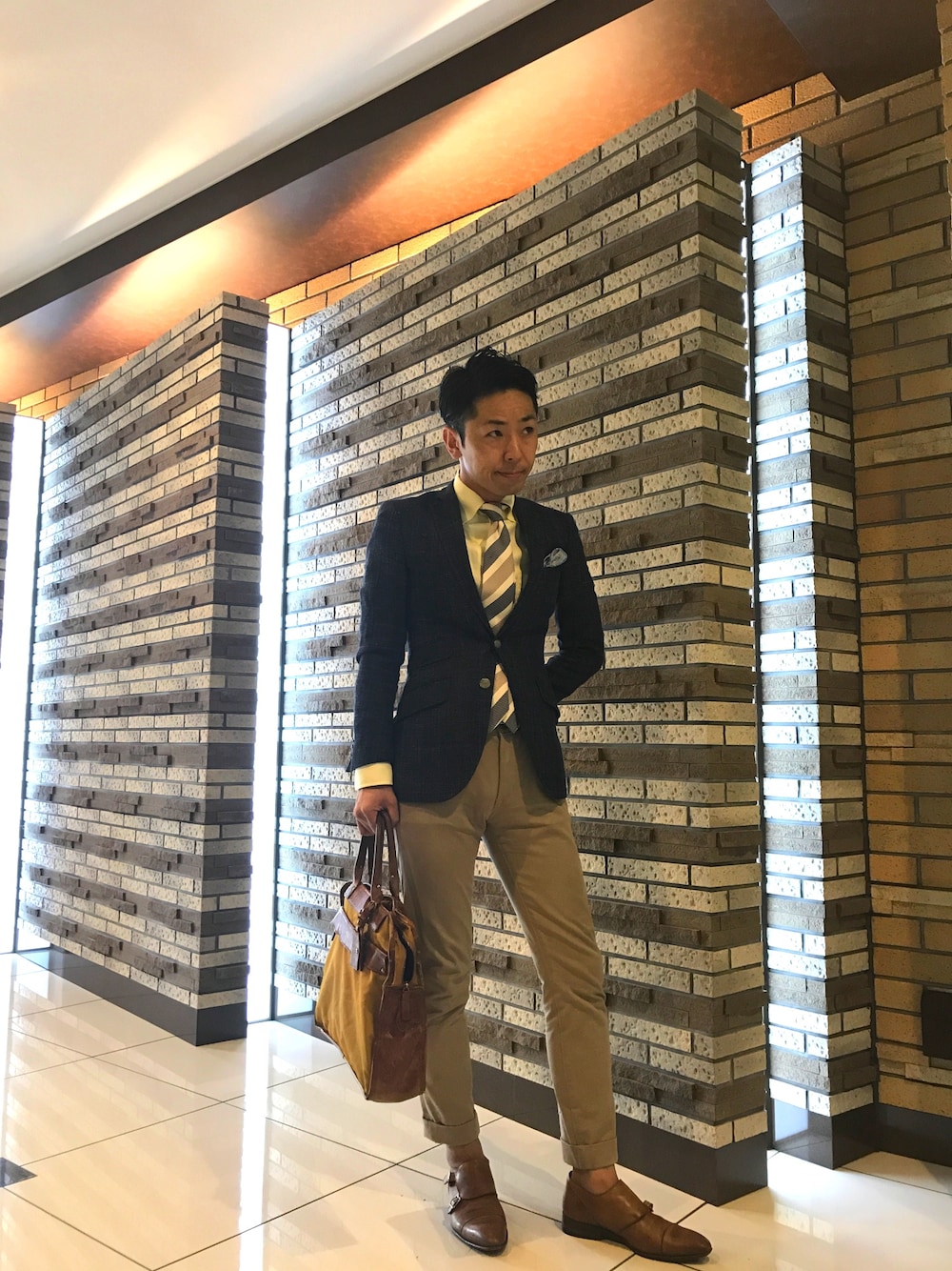 ブルー系のデニムジャケット、ベージュ系のその他パンツ、オレンジ系のビジネスバッグを着用したメンズの夏コーディネートの1枚目の写真