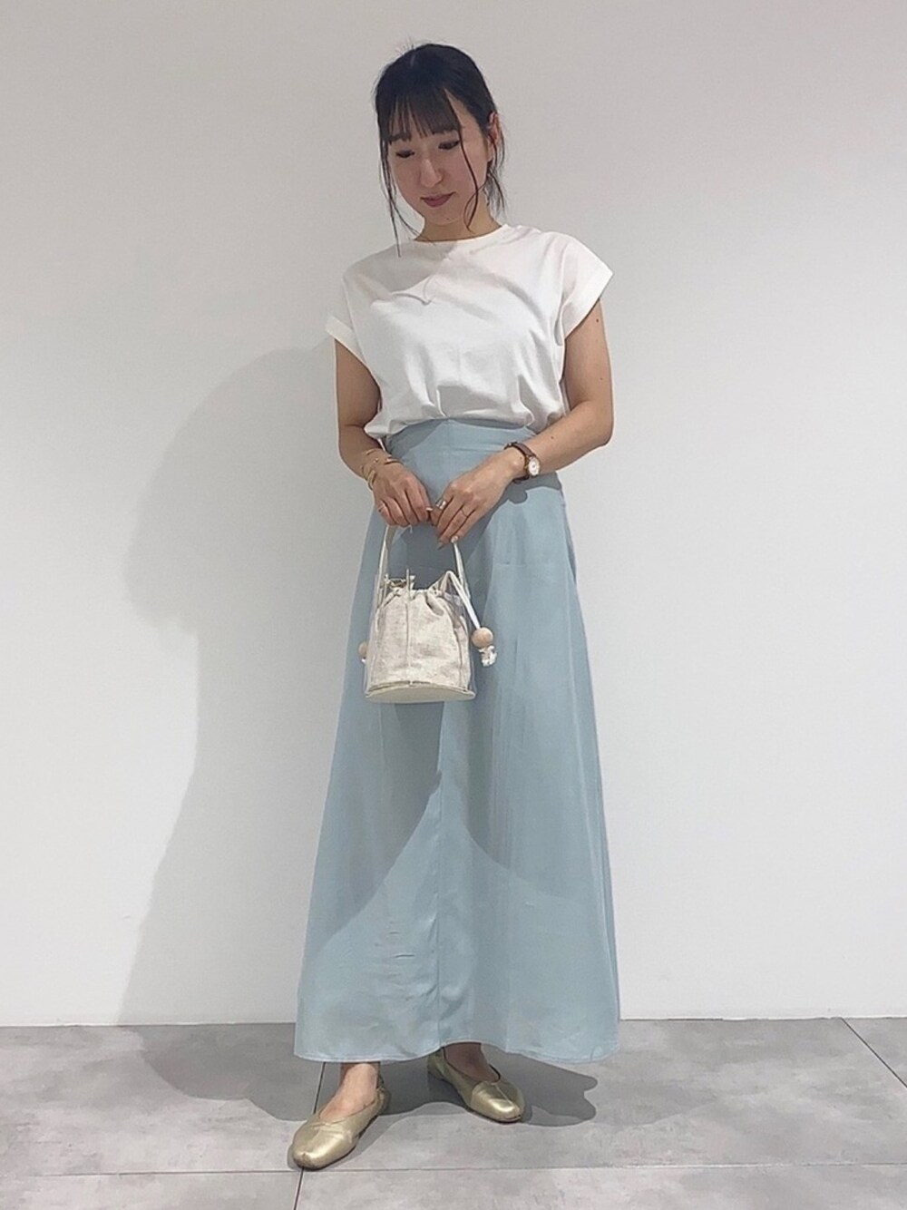 その他のハンドバッグ、ゴールド系のパンプス、グリーン系のスカートを着用したレディースの夏コーディネートの1枚目の写真