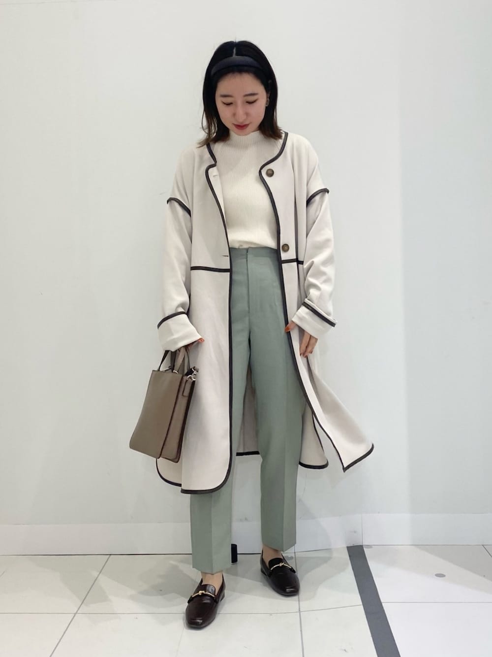 グリーン系のその他パンツ、ホワイト系のニット/セーター、ブラック系のその他アウターを着用したレディースの春コーディネートの1枚目の写真