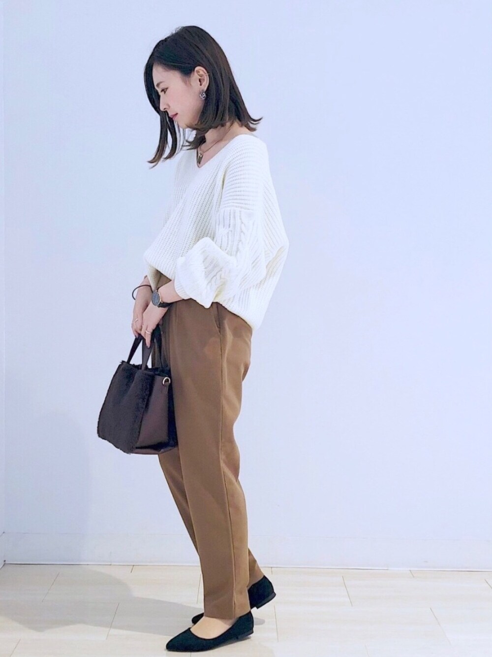 ホワイト系のニット/セーター、イエロー系のその他パンツ、ブラウン系のハンドバッグを着用したレディースの冬コーディネートの1枚目の写真