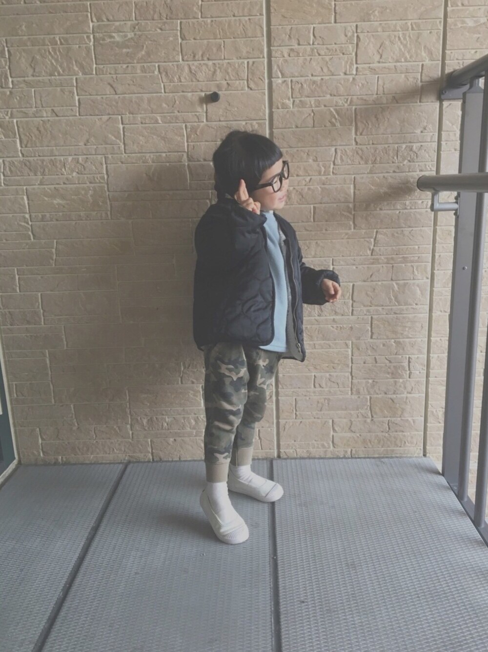 ブルー系のトップス、ブラック系のナイロンジャケット、グリーン系のその他パンツを着用したキッズの冬コーディネートの1枚目の写真