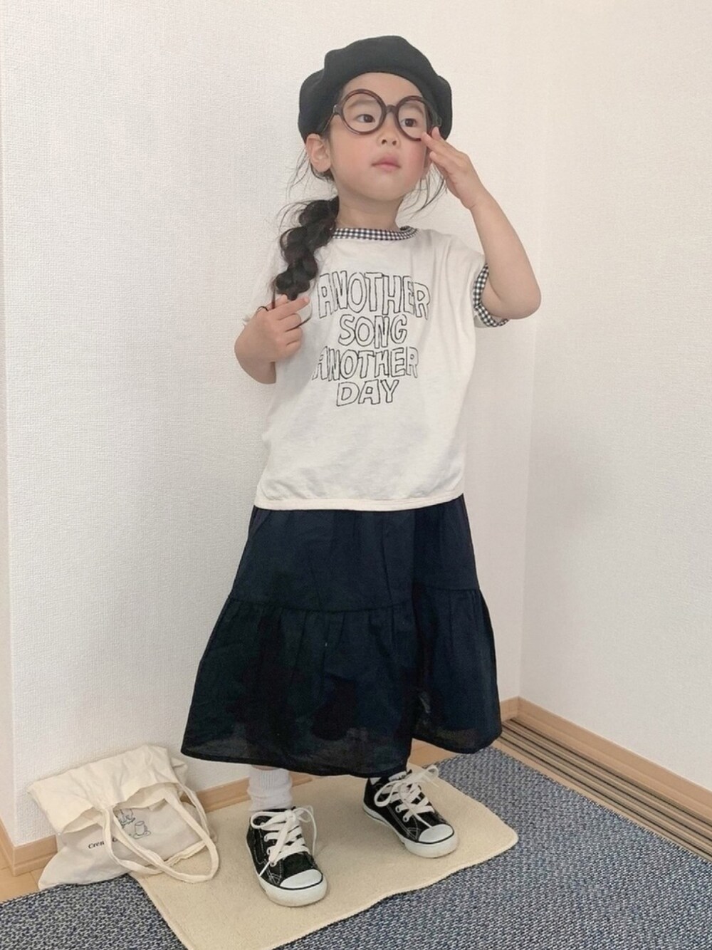 ブラック系のワンピース/ドレス、ホワイト系のエコバッグ/サブバッグ、ホワイト系のTシャツ/カットソーを着用したキッズの春コーディネートの1枚目の写真