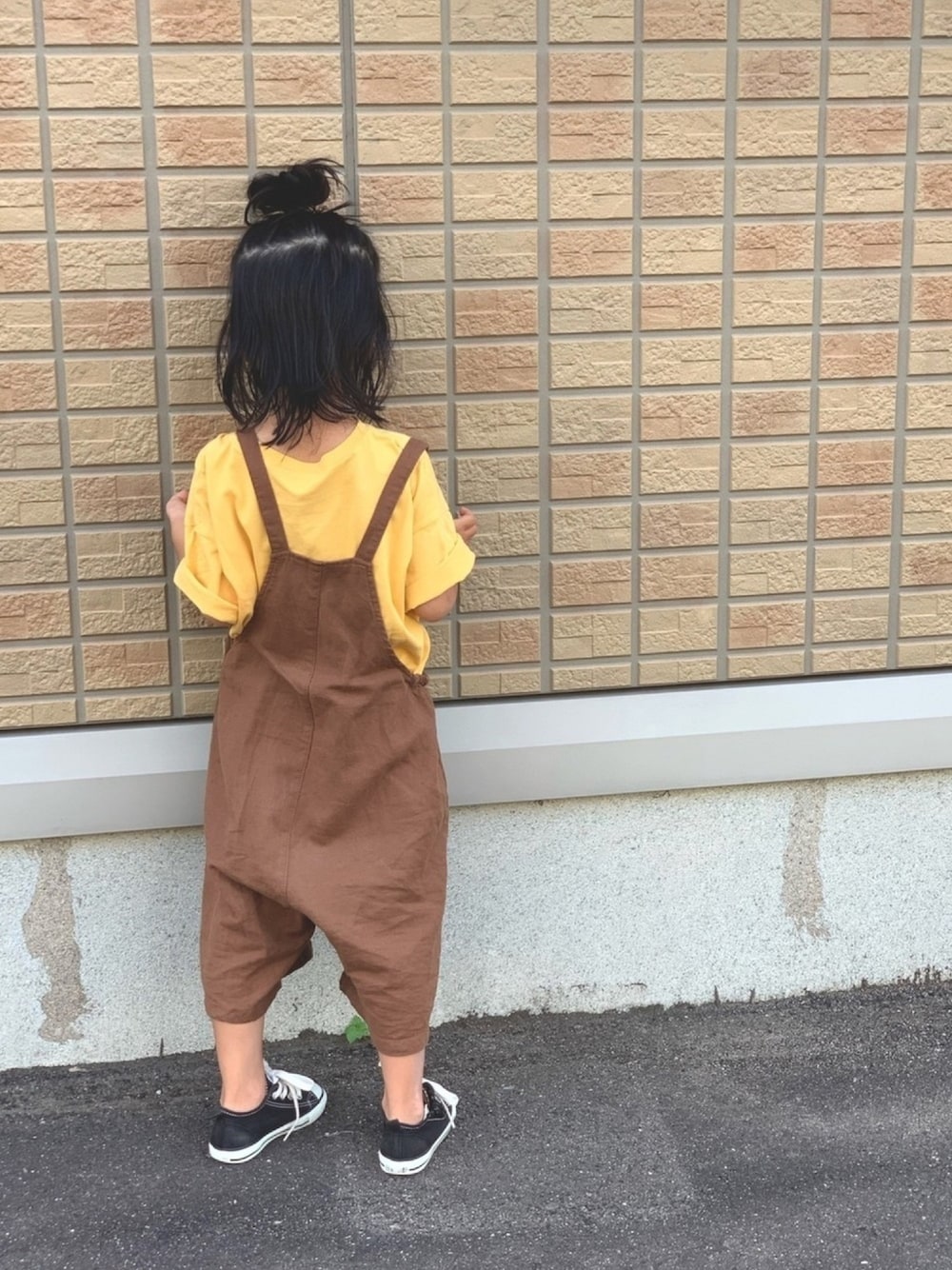 ブラウン系のサロペット/オーバーオール、イエロー系のTシャツ/カットソー、ブラック系のスニーカーを着用したキッズの夏コーディネートの1枚目の写真