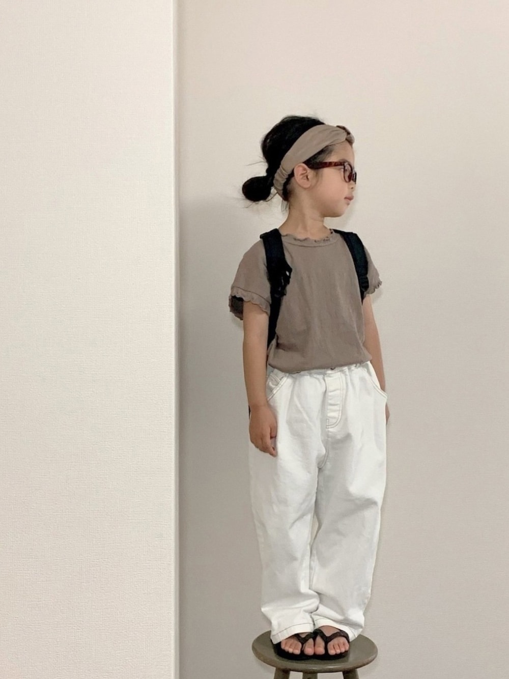 ベージュ系のTシャツ/カットソー、ホワイト系のデニムパンツ、ブラック系のバックパック/リュックを着用したキッズの夏コーディネートの1枚目の写真