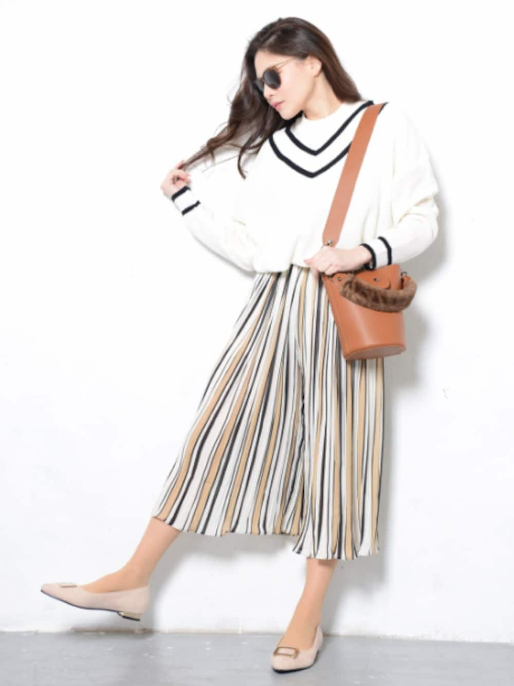 ホワイト系のトップス、オレンジ系のパンツ、ブラウン系のバッグを着用したレディースの冬コーディネートの1枚目の写真