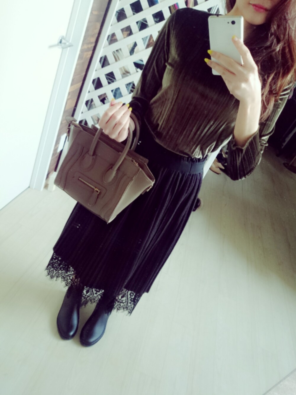 グリーン系のトップス、ブラック系のスカート、ブラウン系のバッグを着用したレディースの冬コーディネートの1枚目の写真