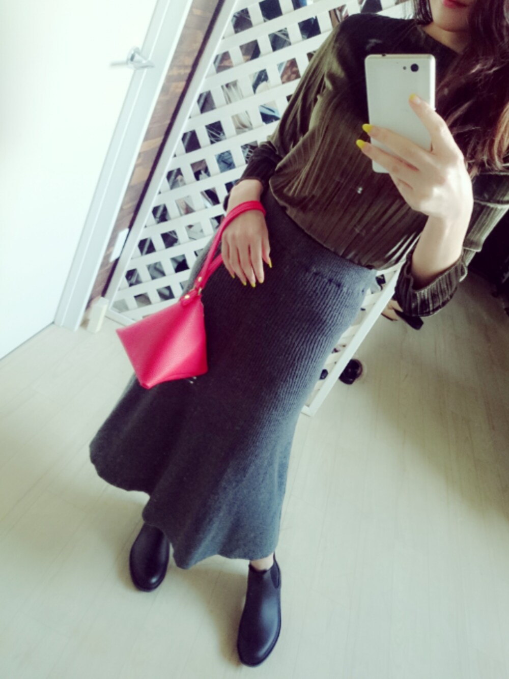 グリーン系のトップス、グレー系のスカート、ブラック系のシューズを着用したレディースの冬コーディネートの1枚目の写真