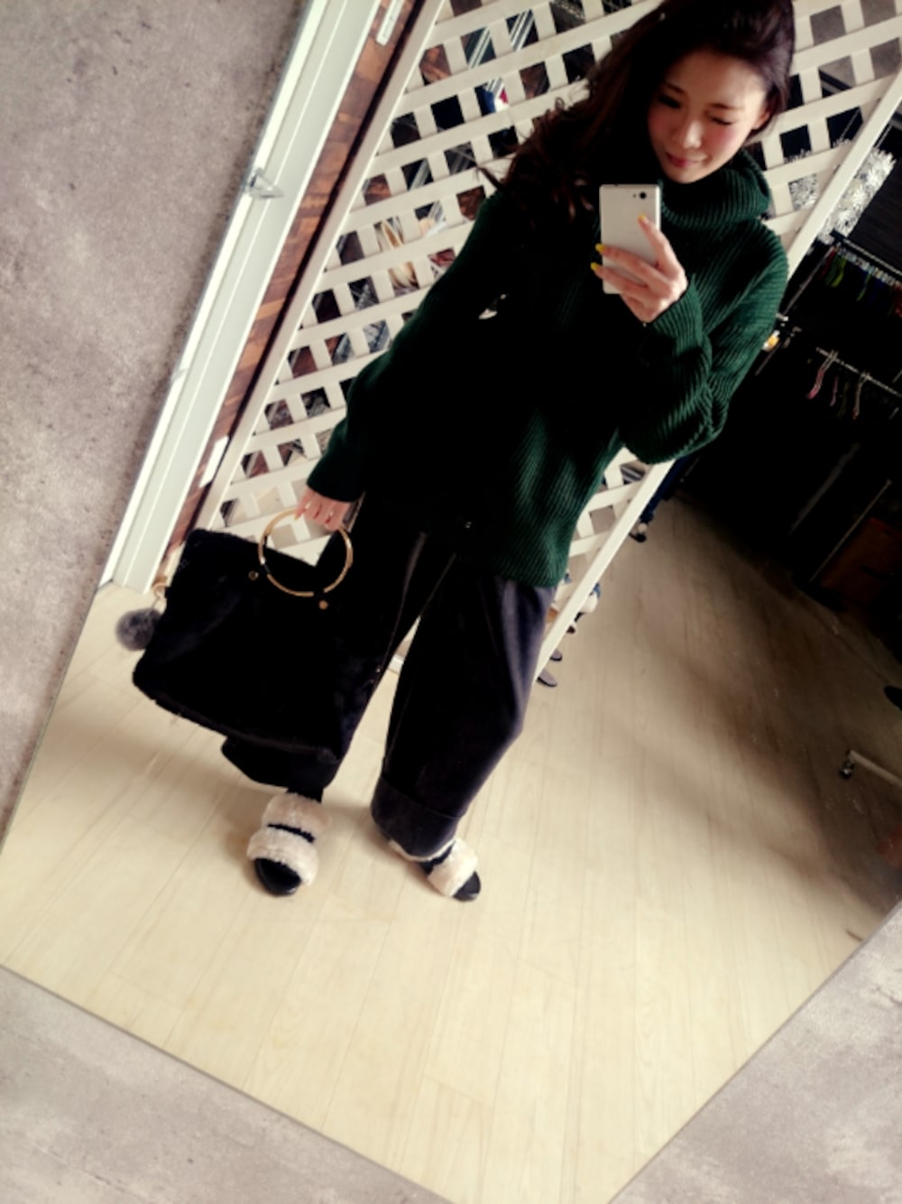 グリーン系のトップス、グレー系のパンツ、ブラック系のバッグを着用したレディースの春コーディネートの1枚目の写真