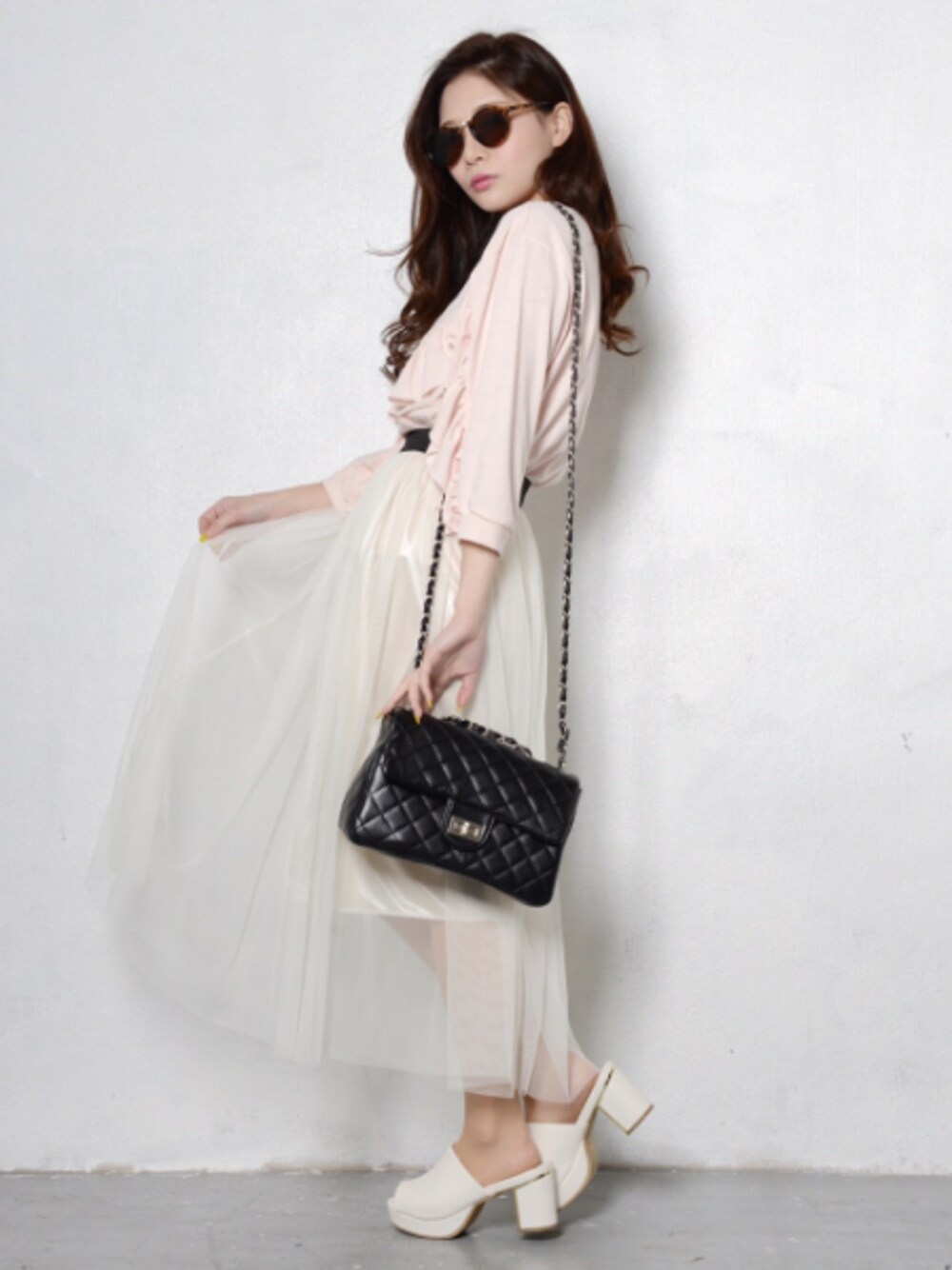 ピンク系のトップス、ホワイト系のスカート、ブラック系のバッグを着用したレディースの春コーディネートの1枚目の写真