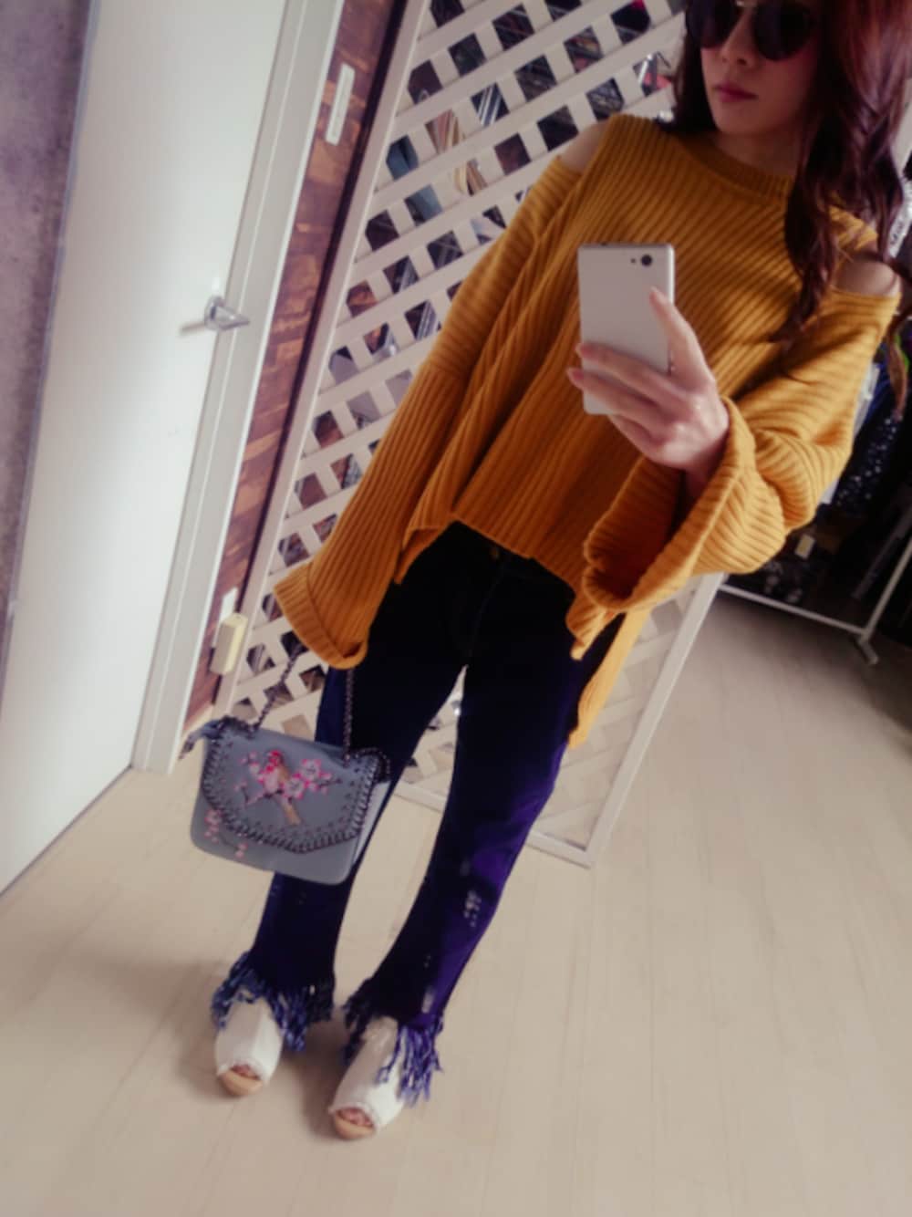 オレンジ系のトップス、ブルー系のパンツ、ホワイト系のシューズを着用したレディースの春コーディネートの1枚目の写真