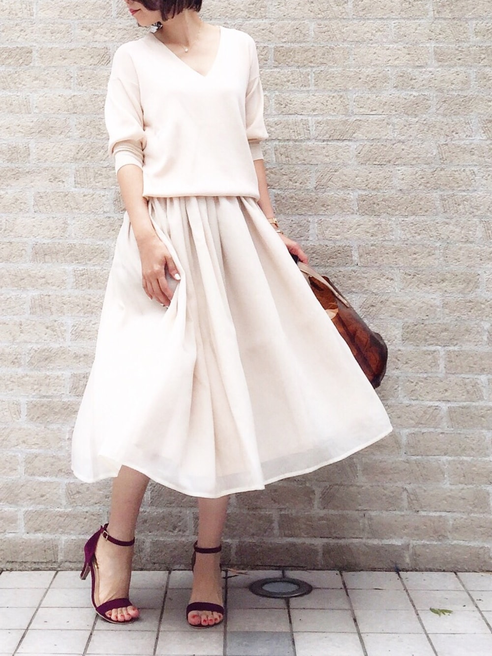 ベージュ系のセットアップ、ブラウン系のトートバッグ、パープル系のサンダルを着用したレディースの春コーディネートの1枚目の写真